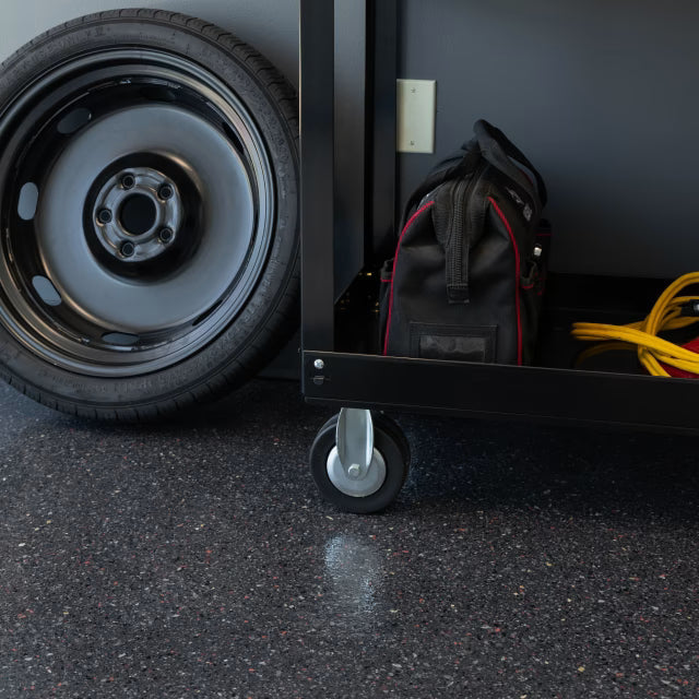 Close-up of Blacktop hybrid epoxy flooring showing red, orange, and gray flake accents over black.