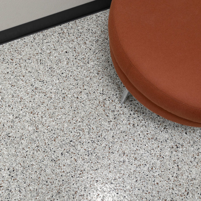  Installed Coyote flake epoxy floor in a commercial room with black wall and office table.